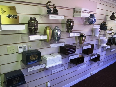 Shelves displaying assorted urns and memorial boxes in a showroom