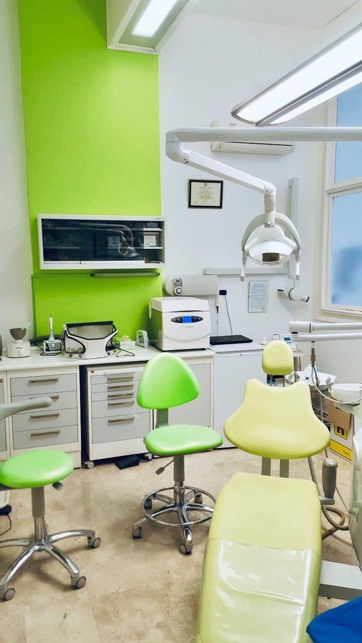 Clinica dentistica di un verde brillante, completa di poltrona, lampada per le visite, armadietti e strumenti.