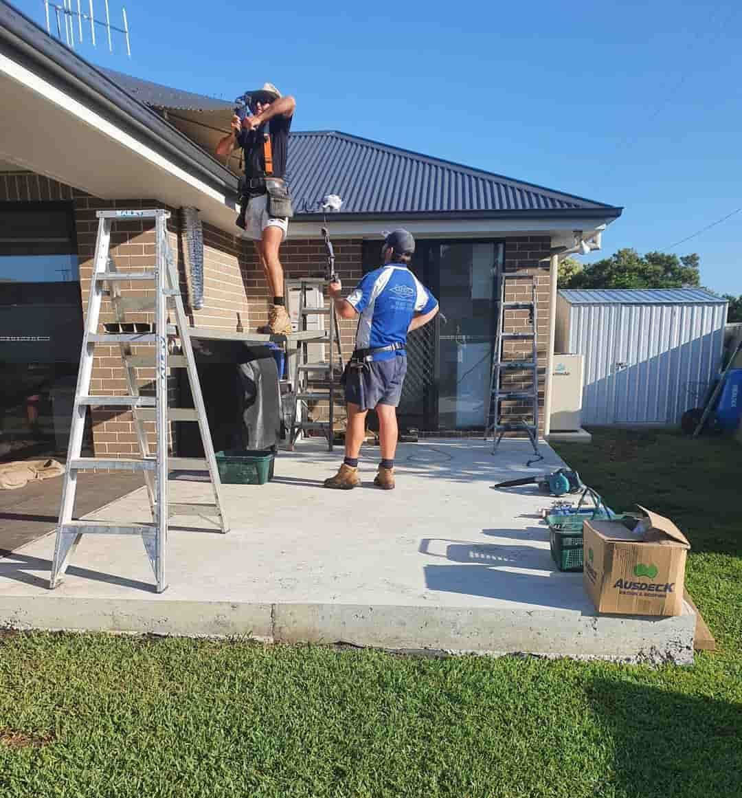 Two Men Are Working On The Roof Of A House — Caprice Home Additions In Forster, NSW