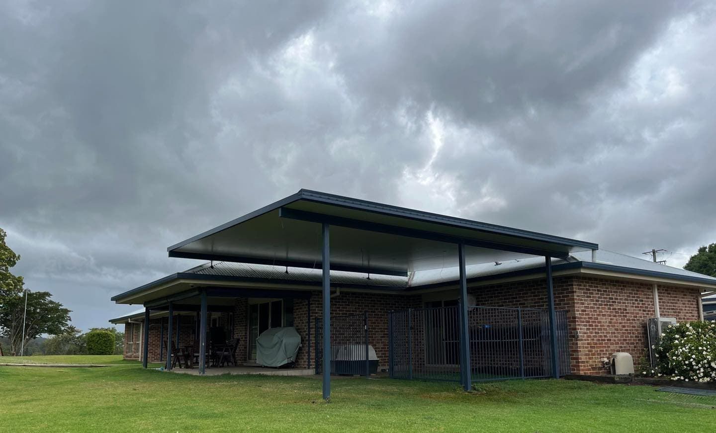 A Brick House With A Covered Porch And A Large Lawn In Front Of It — Caprice Home Additions In Taree, NSW