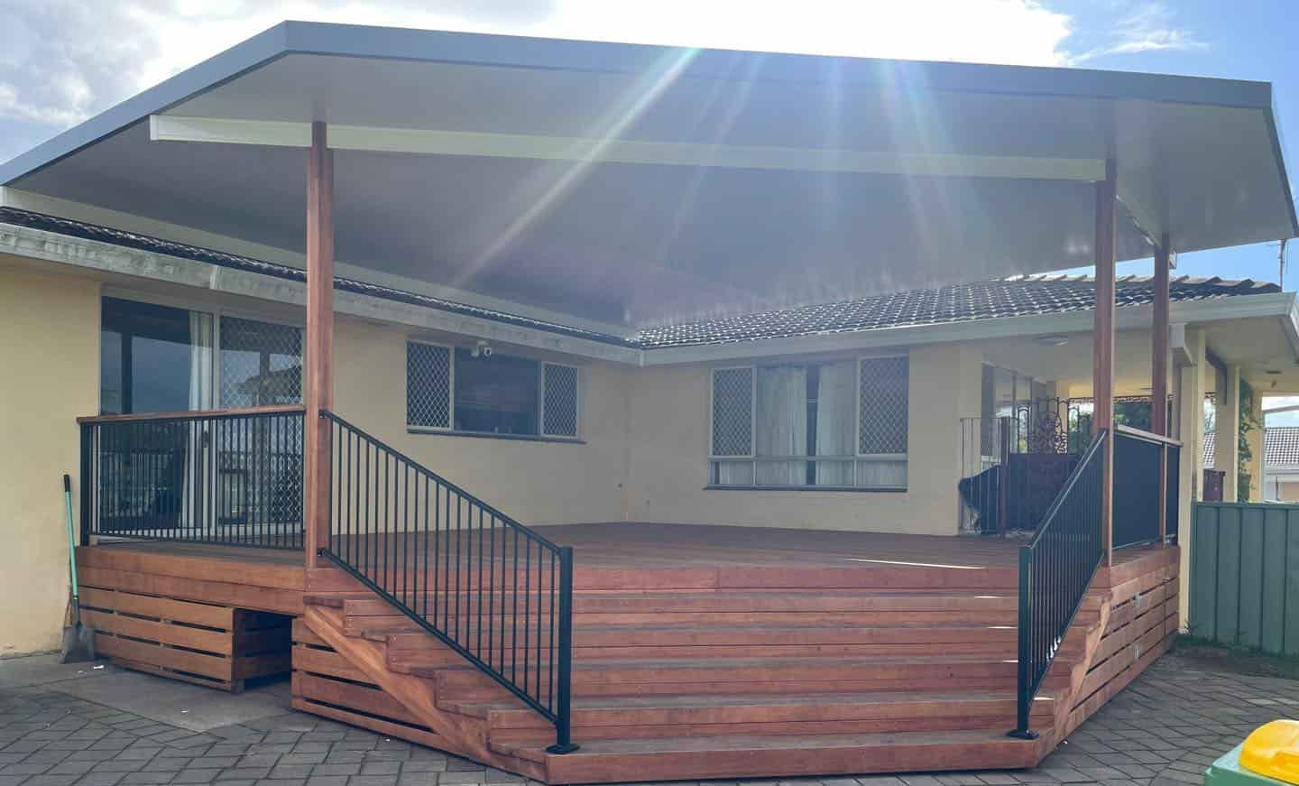A House With A Wooden Deck And Stairs In Front Of It — Caprice Home Additions In Forster, NSW