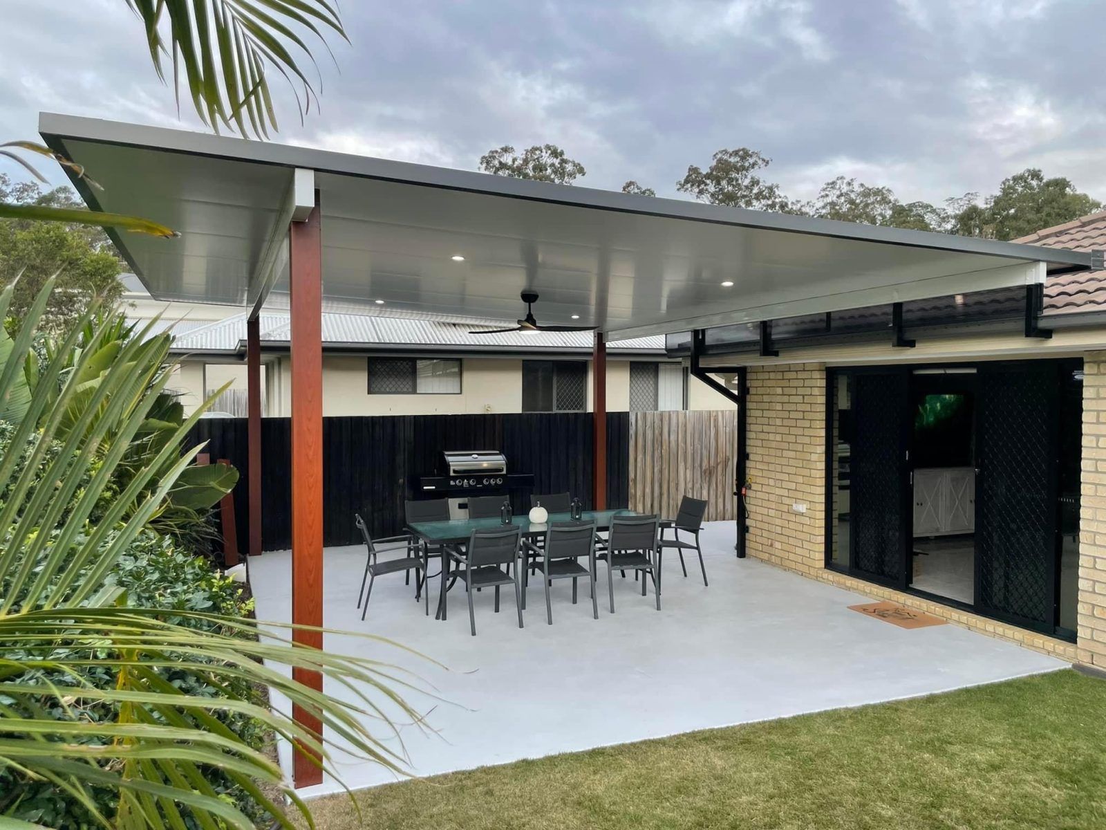 A Man Is Standing On A Patio Next To A Swimming Pool — Caprice Home Additions In Old Bar, NSW