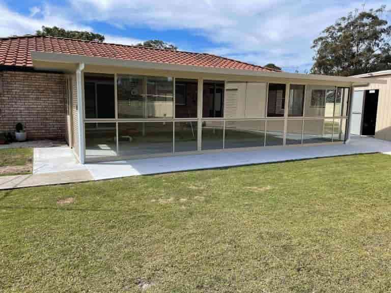 A House With A Screened In Porch And A Large Lawn In Front Of It — Caprice Home Additions In Taree, NSW