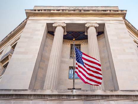 Exterior of a government building with columns and an American flag.