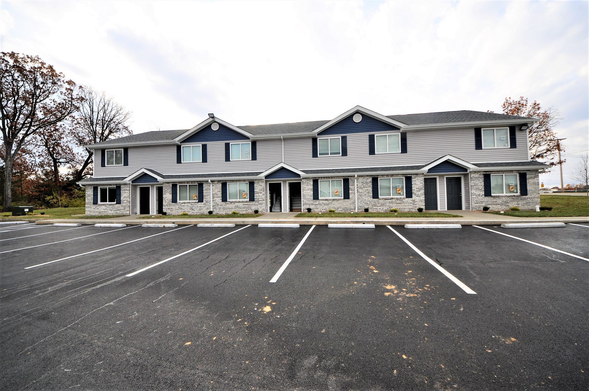 Large gray office building with many windows, seen across an empty parking lot on an overcast day