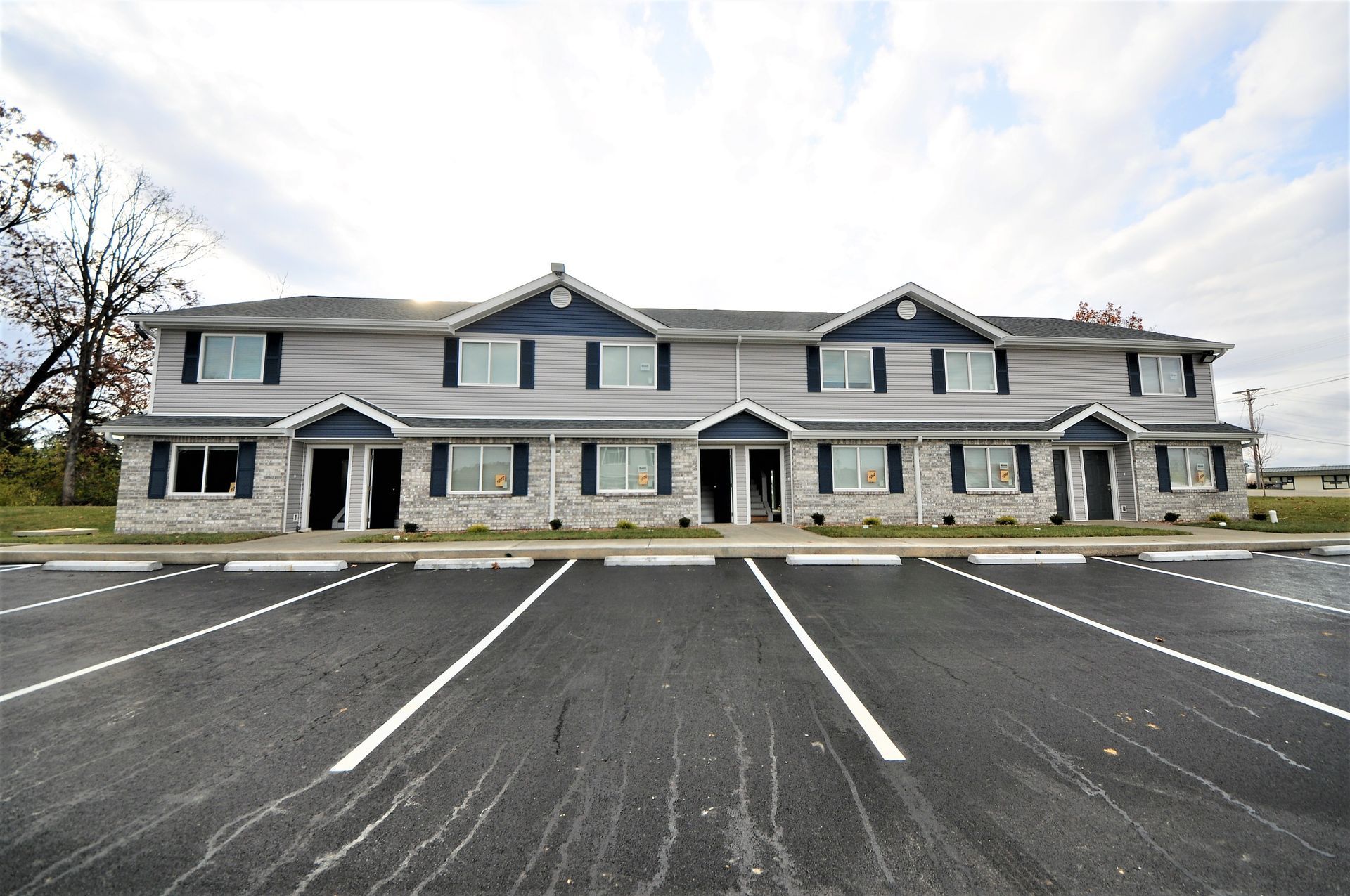 Large two-story gray office building with a mostly empty parking lot in front