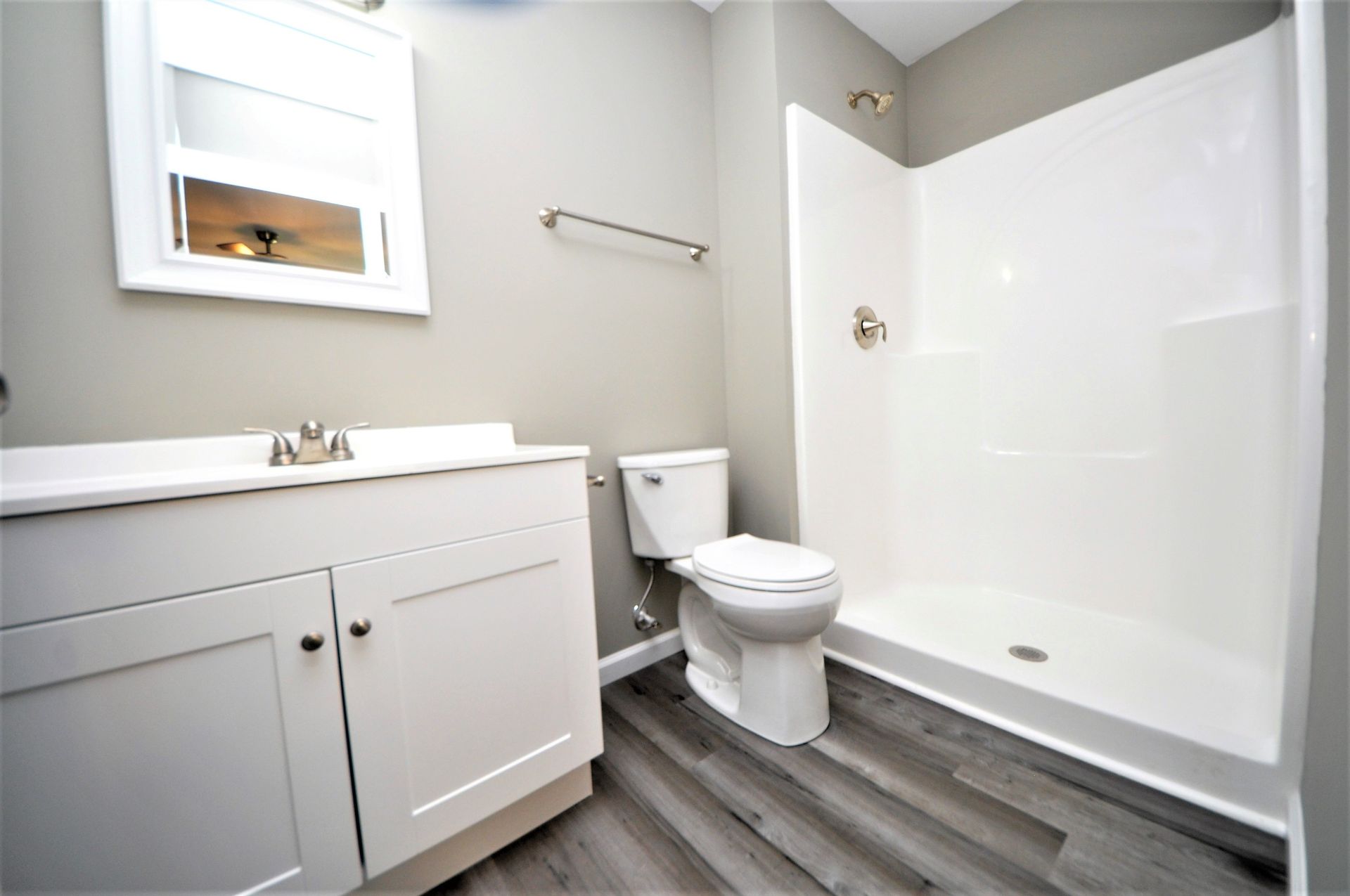 Modern bathroom with white vanity, toilet, and shower/tub combo with gray flooring