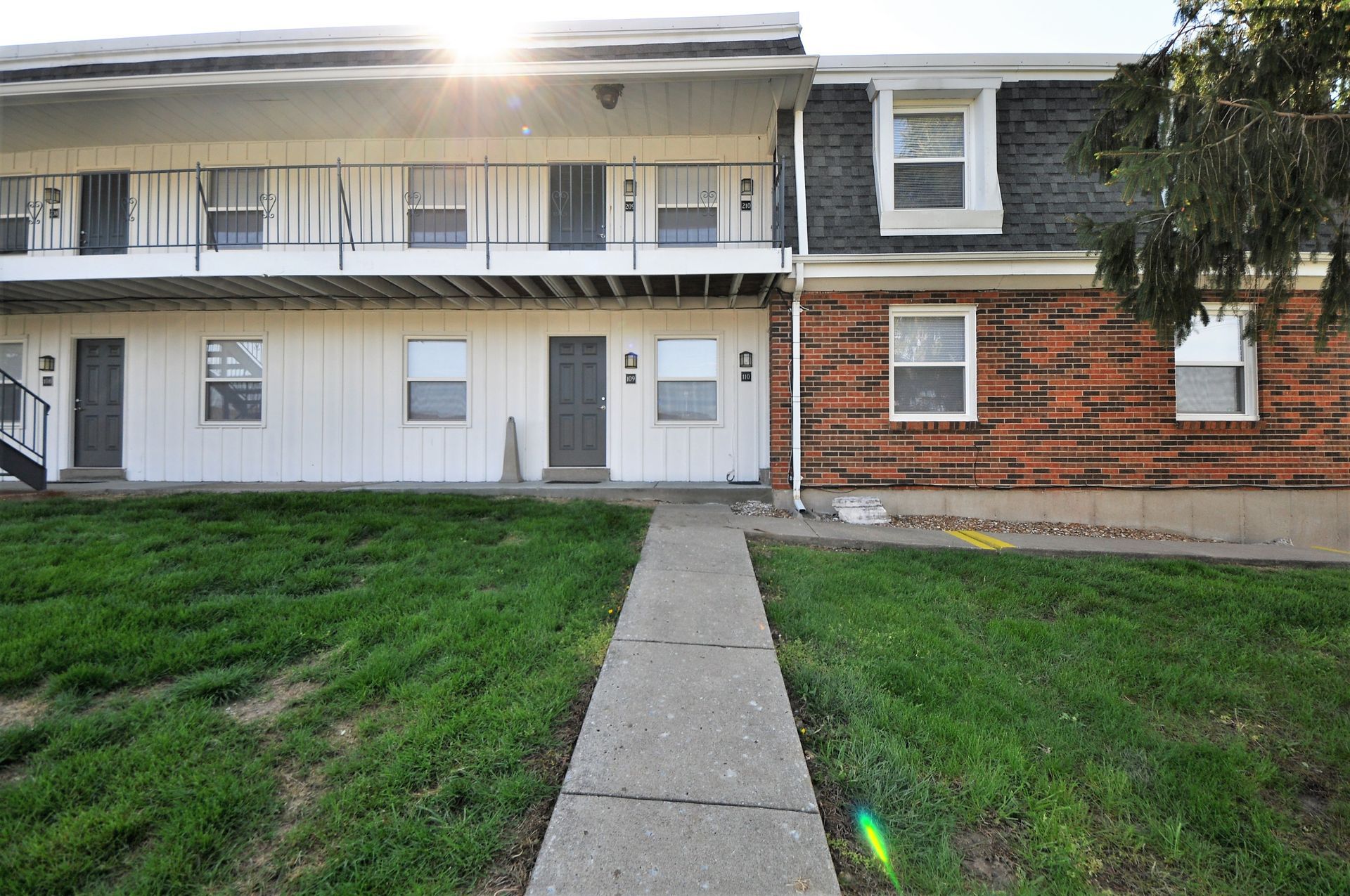 Two-story apartment building with a central sidewalk and grassy front lawn