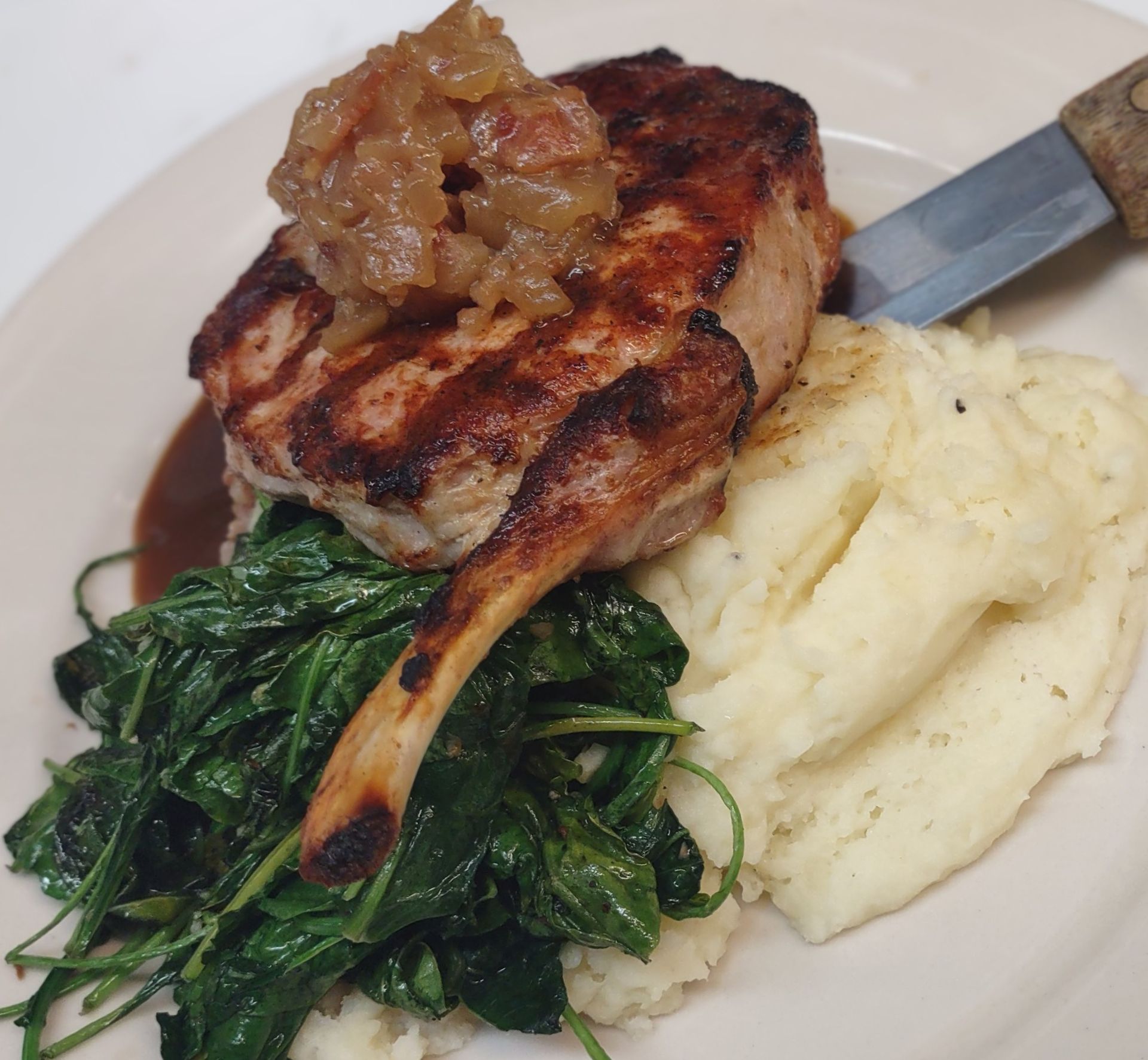 A white plate topped with meat mashed potatoes and spinach