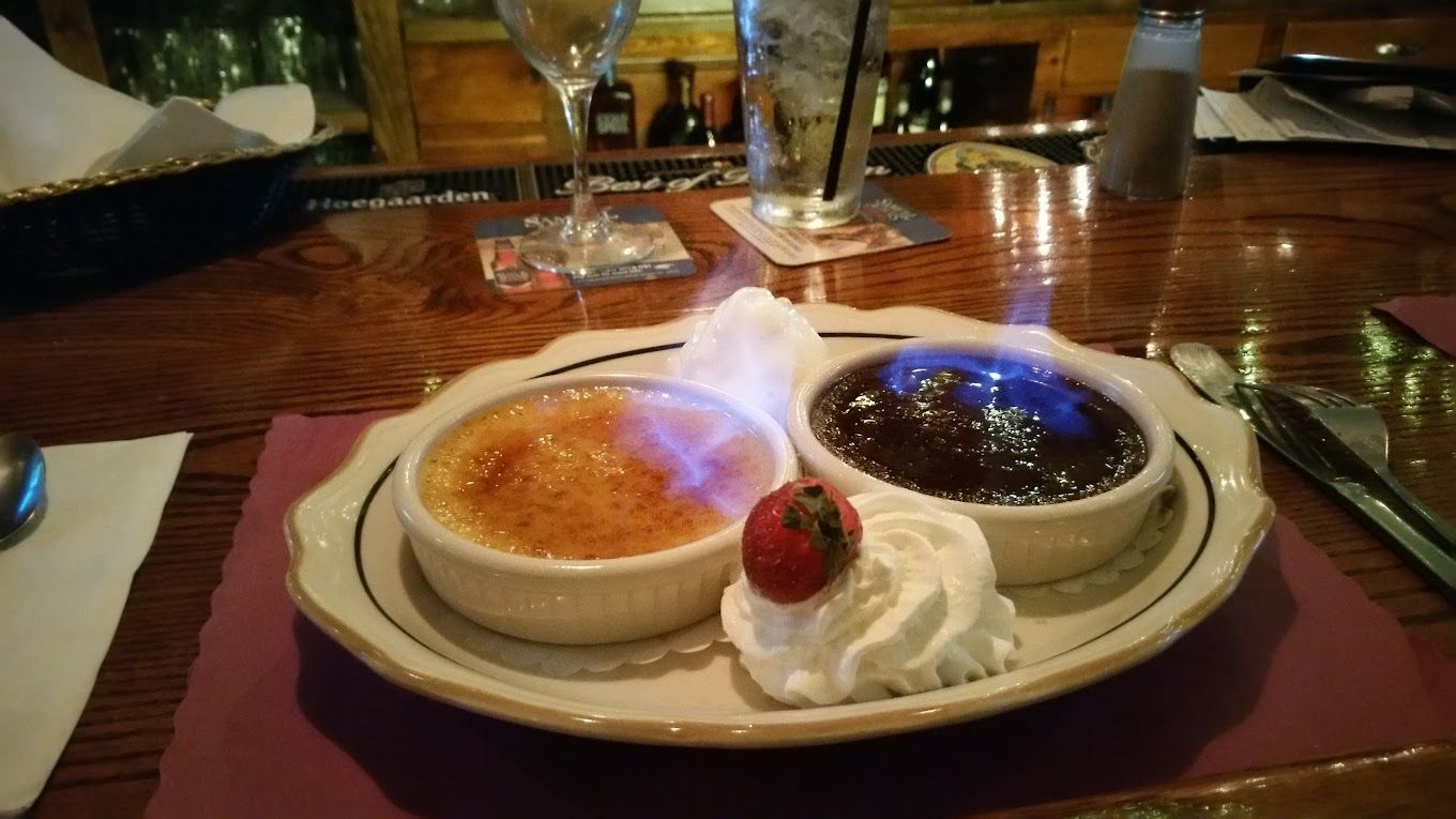A plate of food with a strawberry and whipped cream on a table.