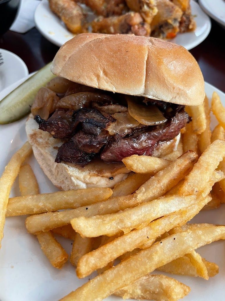 A close up of a hamburger and french fries on a plate.