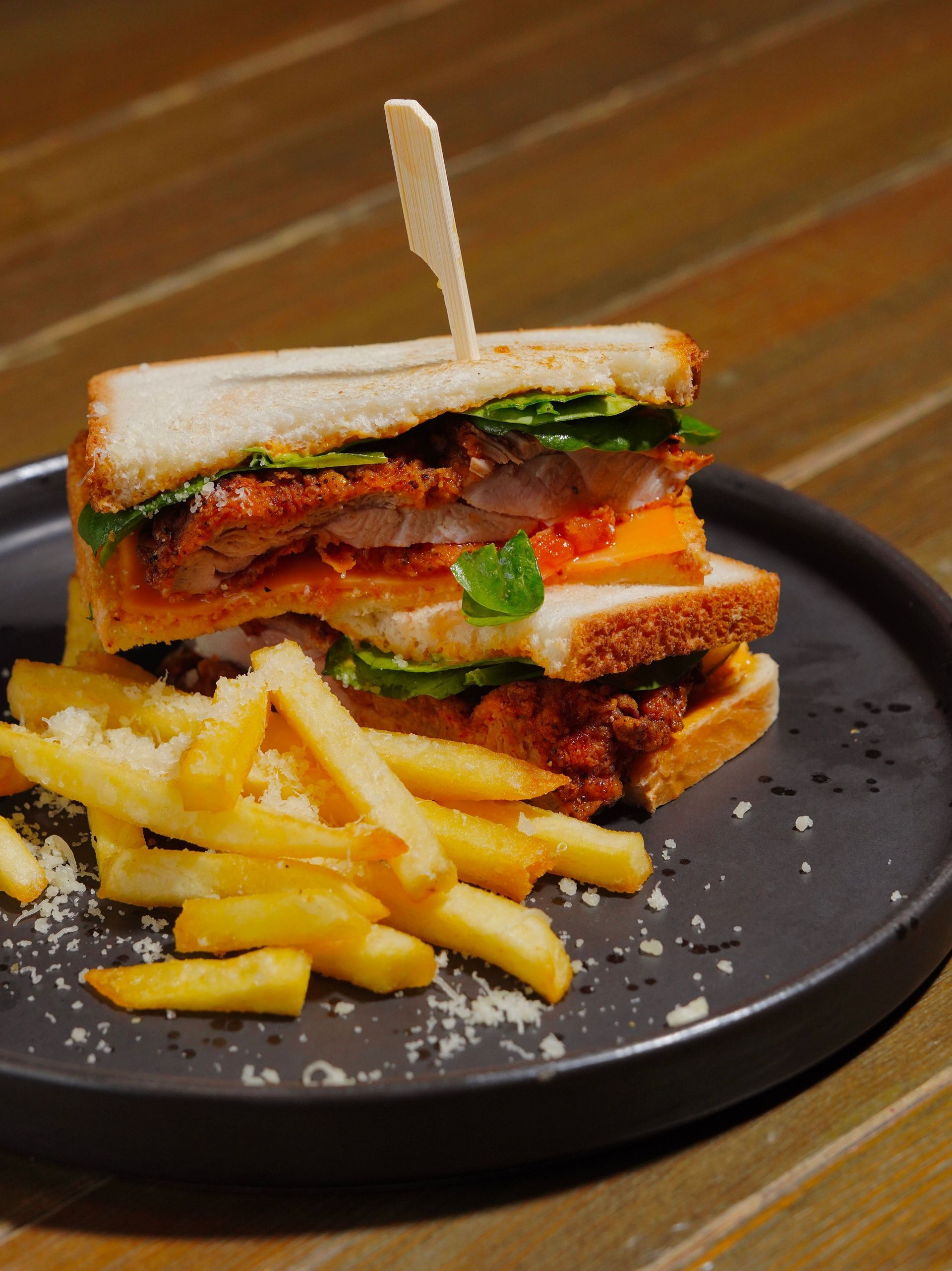 A hamburger and french fries on a white plate with a bud light bottle in the background
