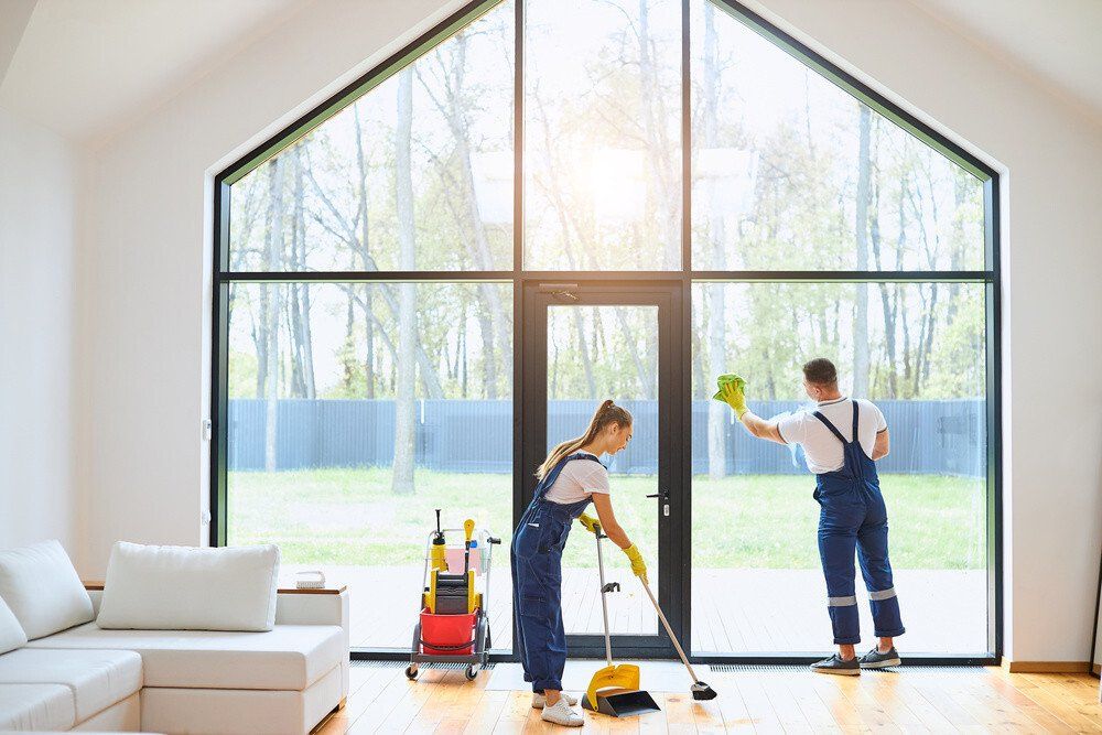 Staff members of Berkshire cleaning mopping the floor and scrubbing the windows during a house cleaning service