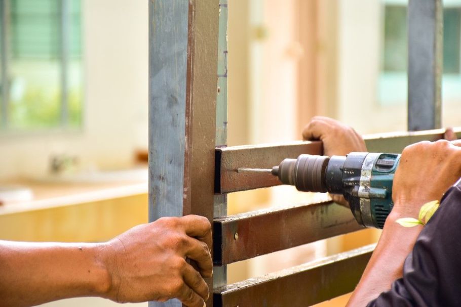 Hands drilling a wooden frame with a power drill near a window
