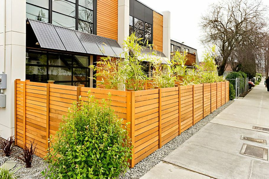 Modern townhouse with orange wooden fence, front garden, and sidewalk on a quiet street