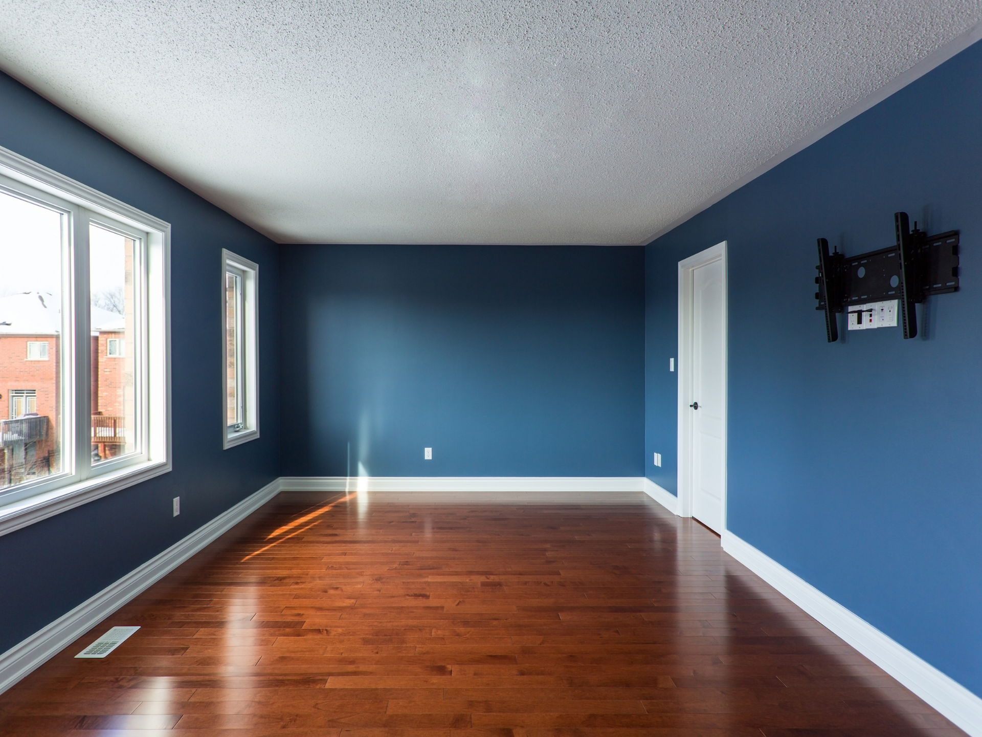 An empty living room with blue walls and hardwood floors