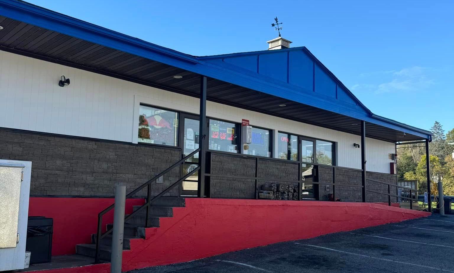 Exterior of a commercial building with blue roof, black trim, and red ramp entrance.