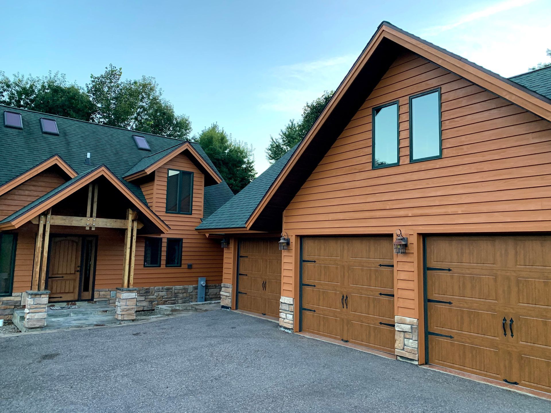 Brown house with two garage doors and a stone driveway.