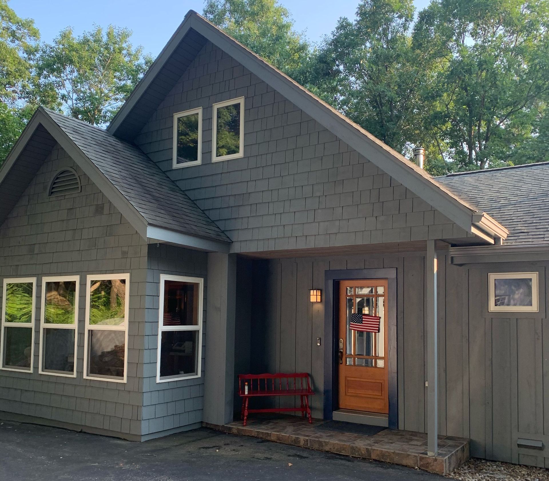Gray cottage with brown door, windows, and red bench.