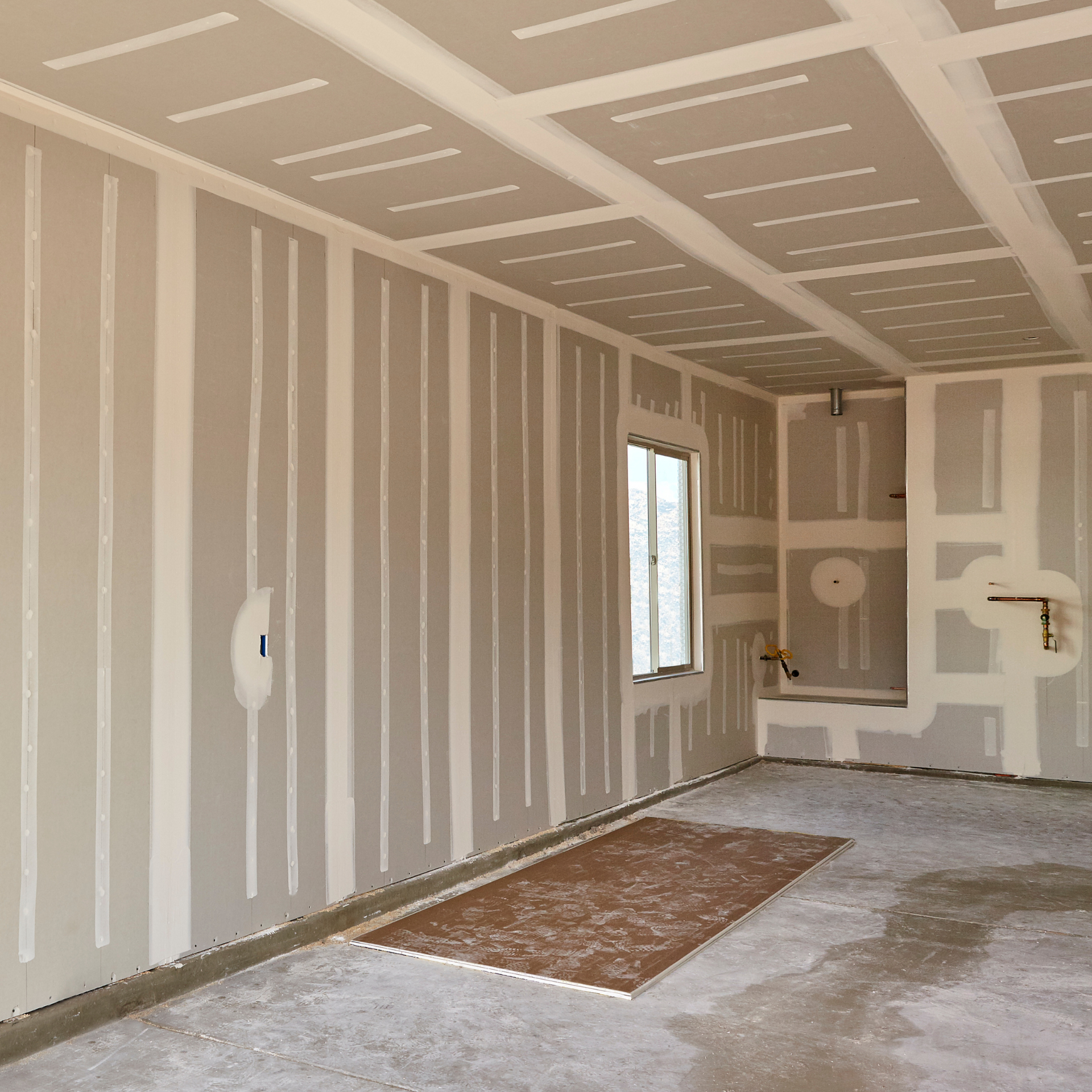 An empty room with drywall walls and a rug on the floor