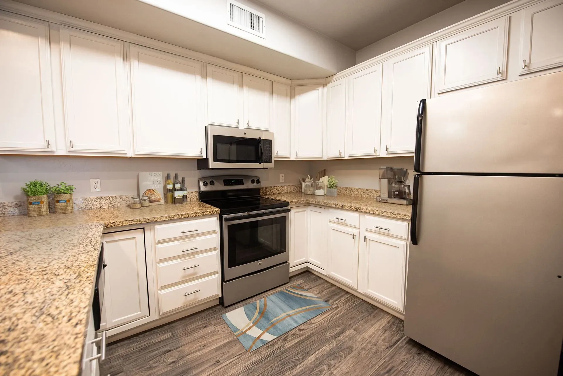 Modern kitchen with white cabinets, granite countertops, stainless steel appliances including a refrigerator, microwave, and stove at Hills at Renaissance, offering pet-friendly apartments in Bountiful, UT.