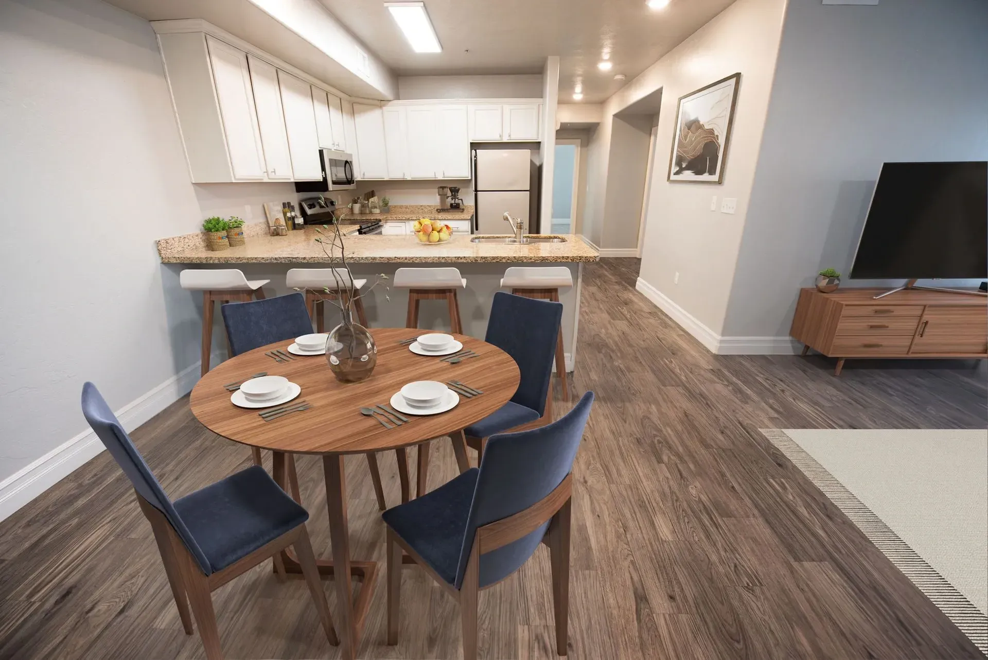 Open-concept dining area and kitchen with a round table, chairs, and breakfast bar at Hills at Renaissance, offering apartments for rent in Bountiful, UT.