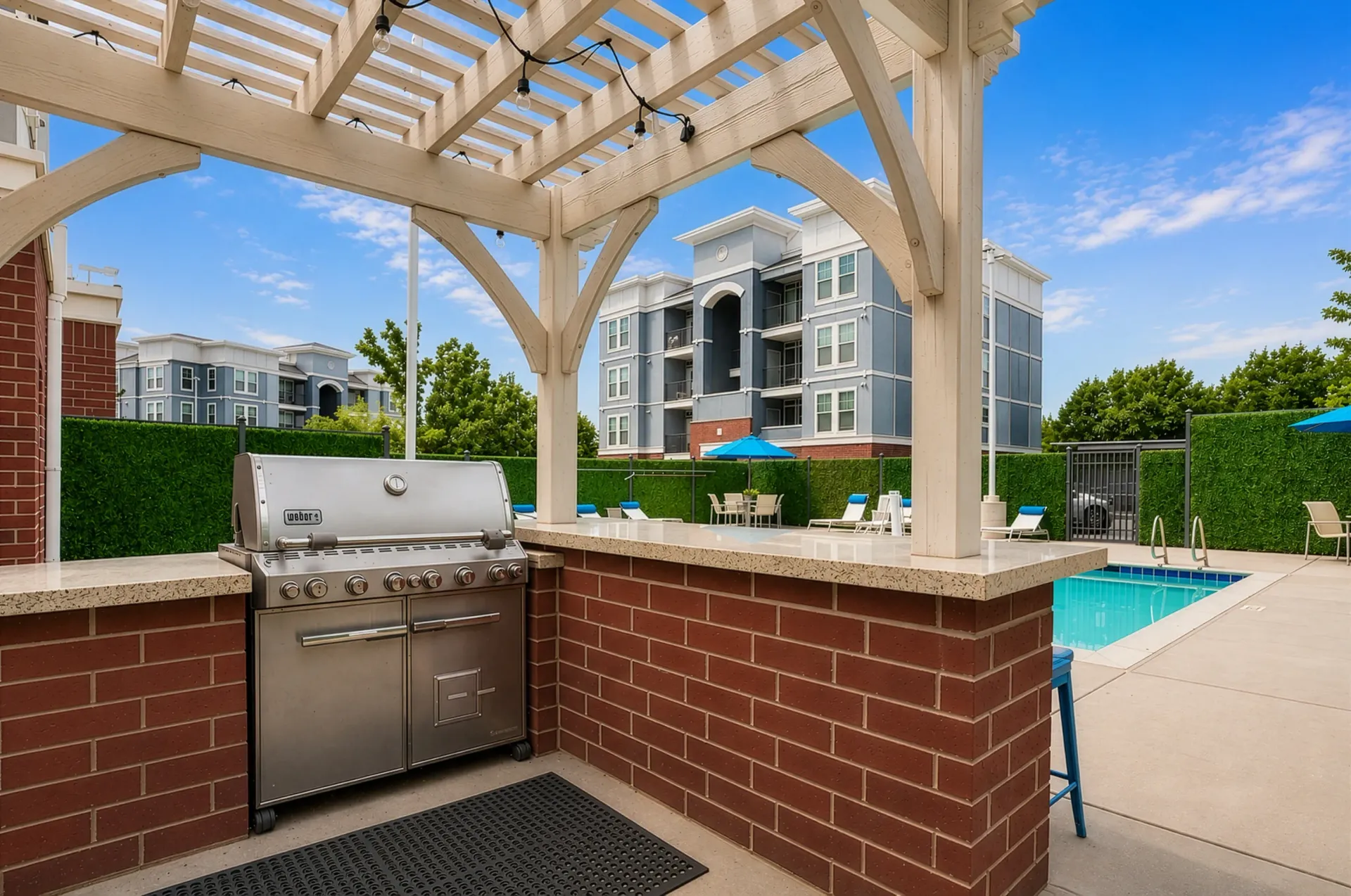 Outdoor grill and pool area with lounge chairs and tables at Hills at Renaissance, offering apartments in Bountiful, UT.
