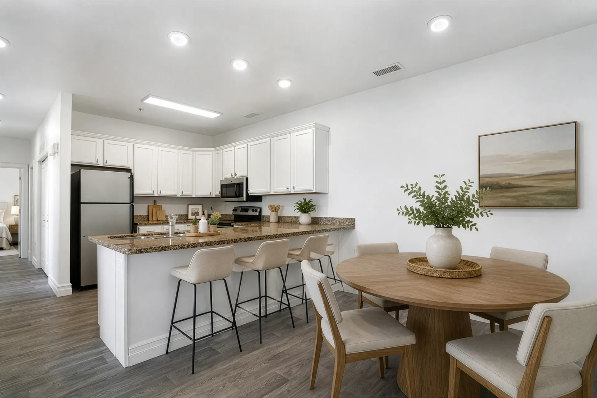 Modern kitchen and dining area with granite countertops, stainless steel appliances, and a round dining table at Hills at Renaissance, offering pet-friendly apartments in Bountiful, UT.