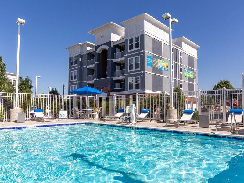 Hills at Renaissance pool area with lounge chairs and a gated apartment building in the background.