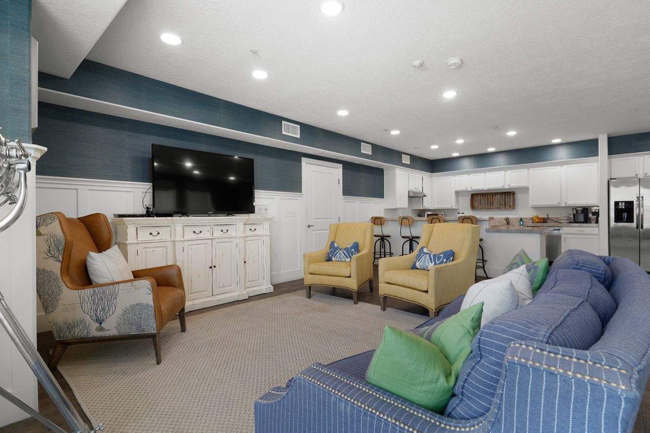 Hills at Renaissance living room with blue accents, a TV, and a kitchen in the background.