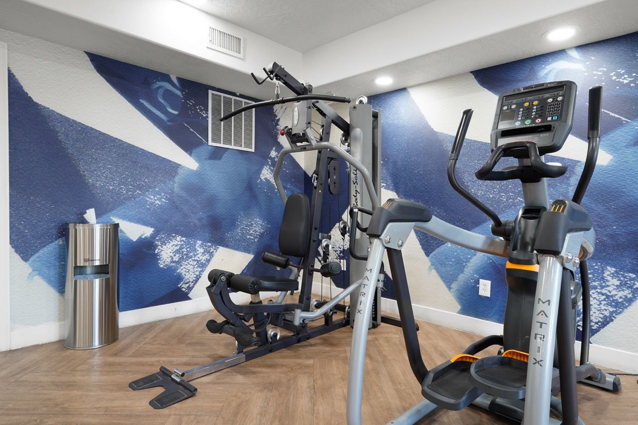 Hills at Renaissance fitness center with cardio machine and weight training equipment against a blue wall.