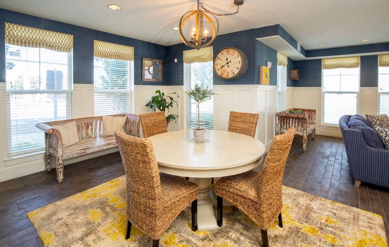Hills at Renaissance lounge with a round dining table, wicker chairs, blue walls, and large windows.