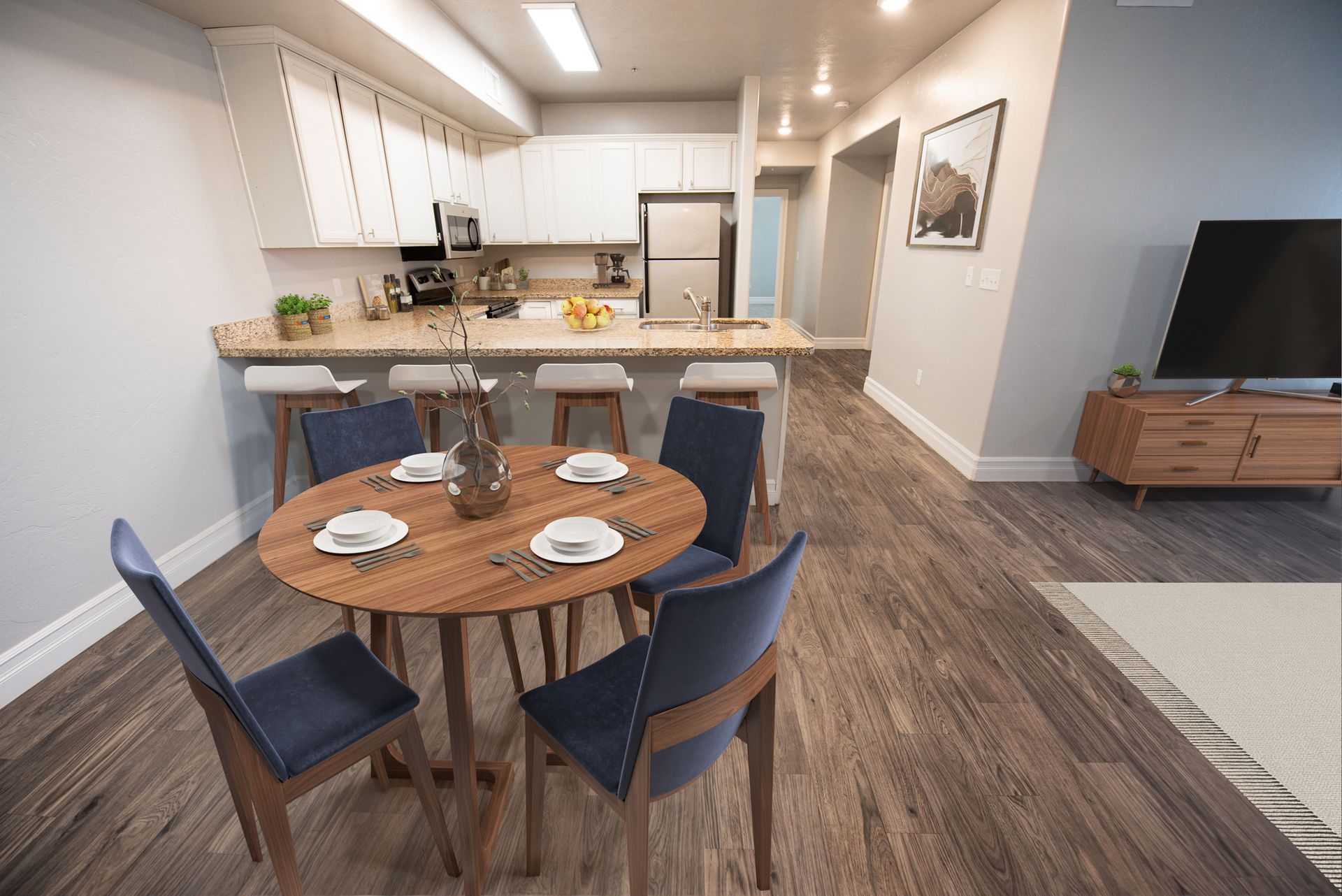 Hills at Renaissance Dining area with round wooden table and blue chairs, leading to a kitchen with a breakfast bar.