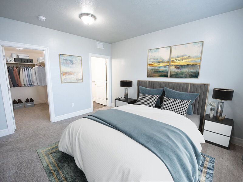 Hills at Renaissance Bedroom in an apartment with a large bed, blue-gray bedding, and an adjacent walk-in closet.