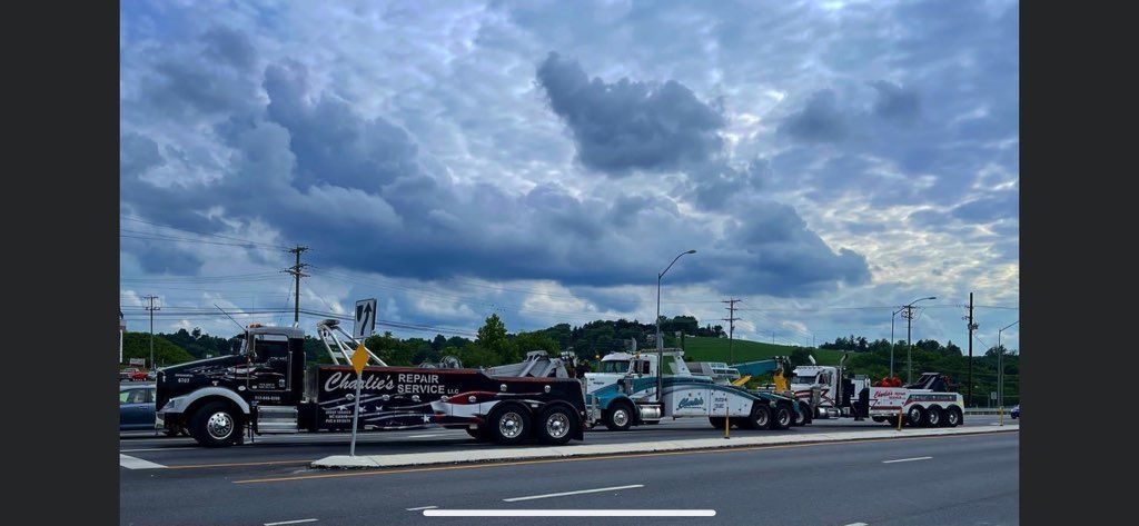 Parked motorcycles and trucks along a road beneath dark, cloudy storm skies