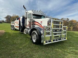 Charlie's Repair Service White and red semi truck parked on grass under a cloudy sky, front view with chrome grille