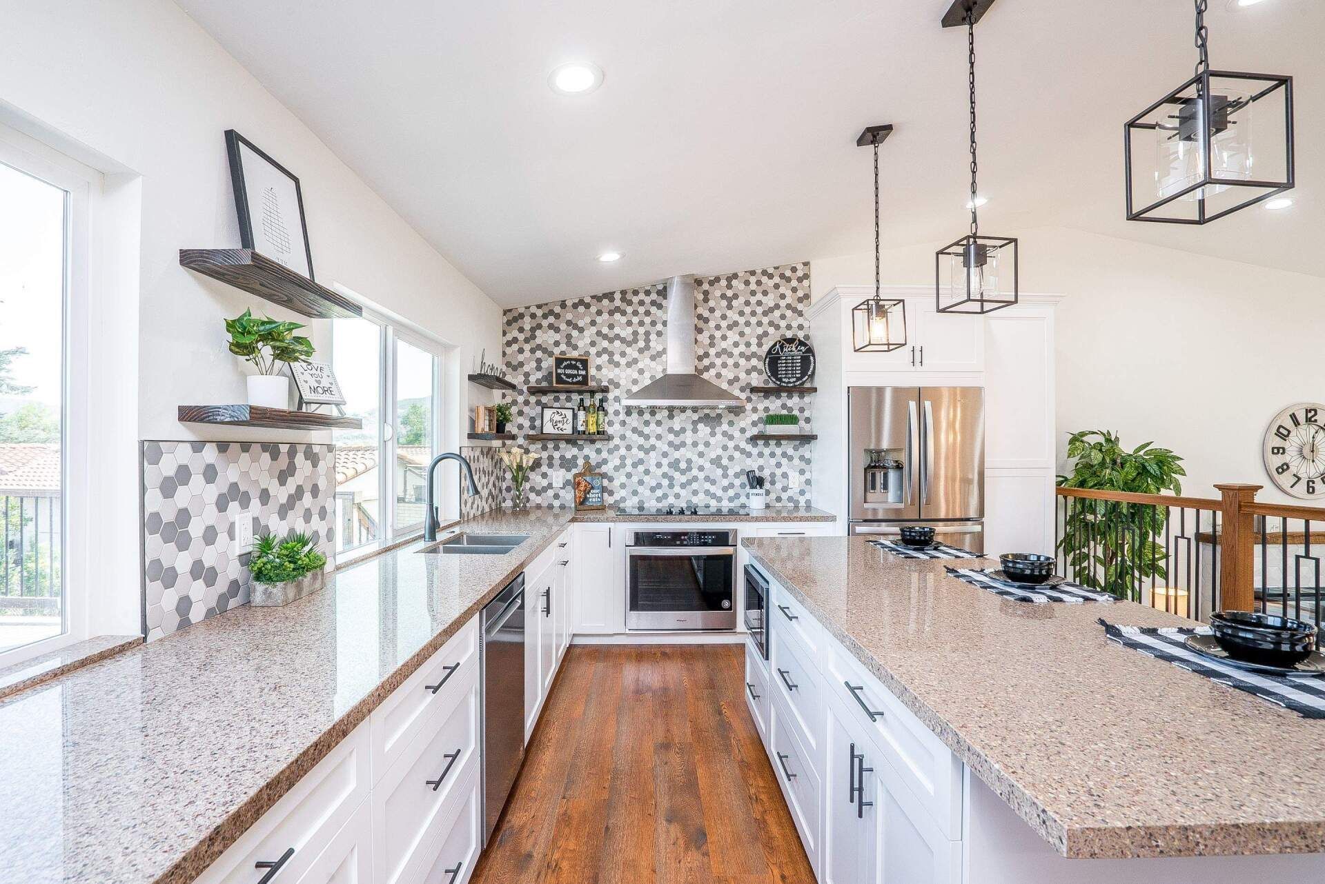 Modern kitchen with white cabinets, speckled countertops, wood floors, and decorative wall tiles.