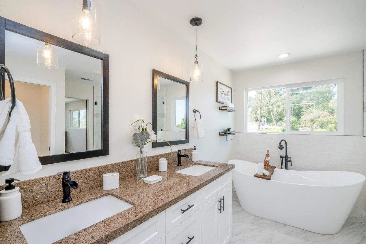 Modern bathroom with white cabinets, brown countertop, soaking tub, and black accents.