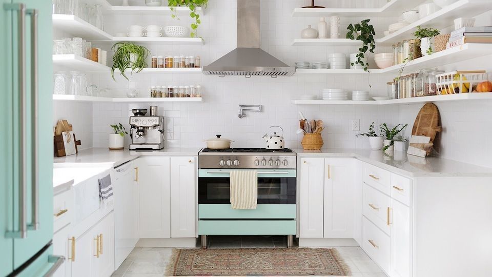 White kitchen with open shelving, mint-colored stove, and plants.