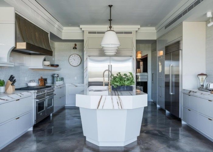 Modern kitchen with gray cabinets, marble countertops, stainless steel appliances, and a geometric island.