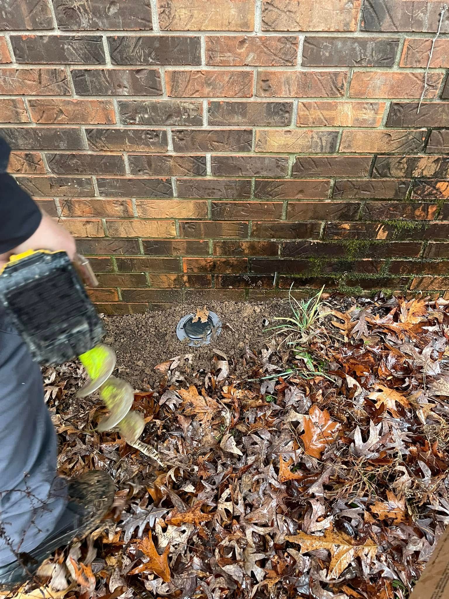 A person is using a drill to drill a hole in a brick wall.