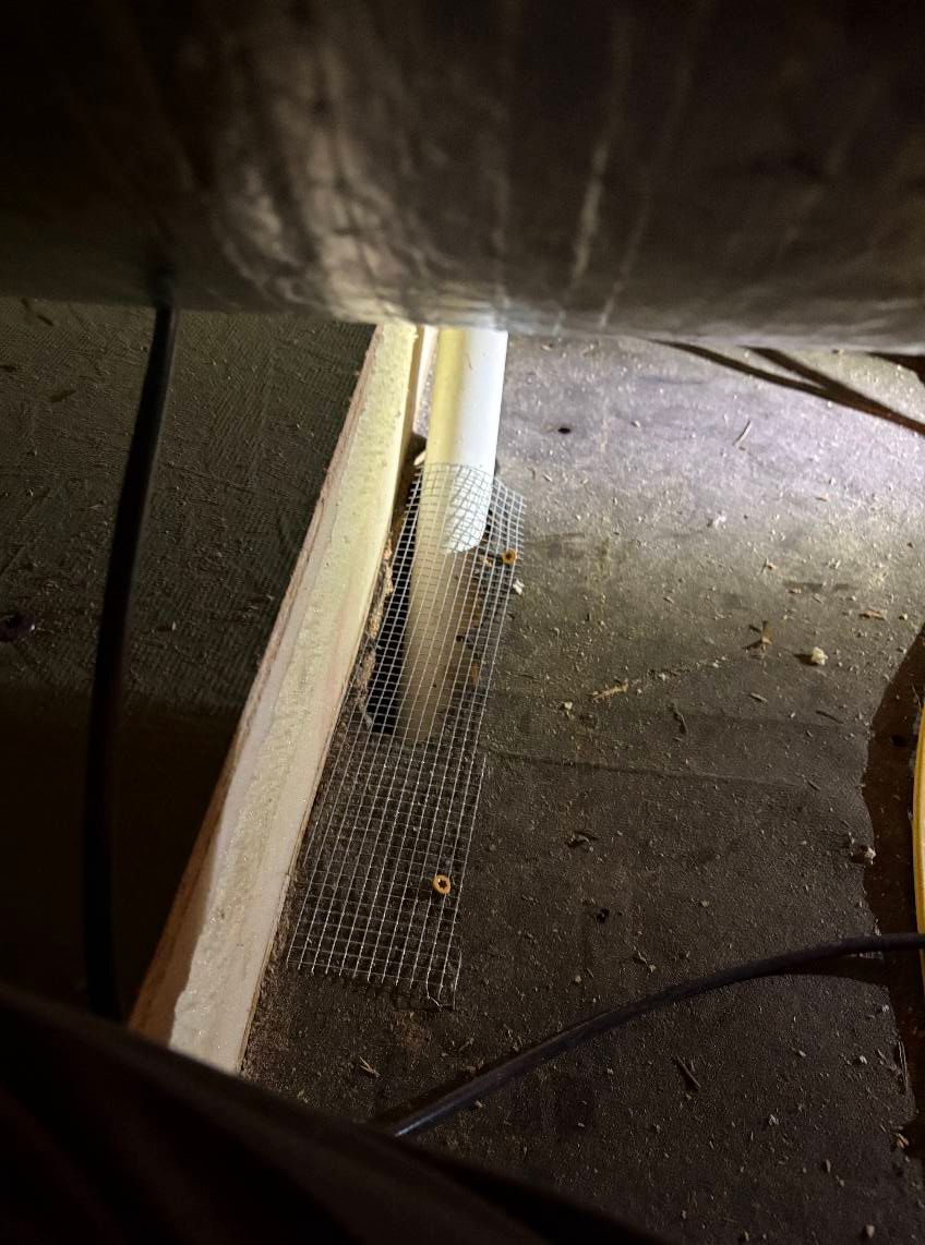 A close up of a metal mesh on the floor next to a pipe.