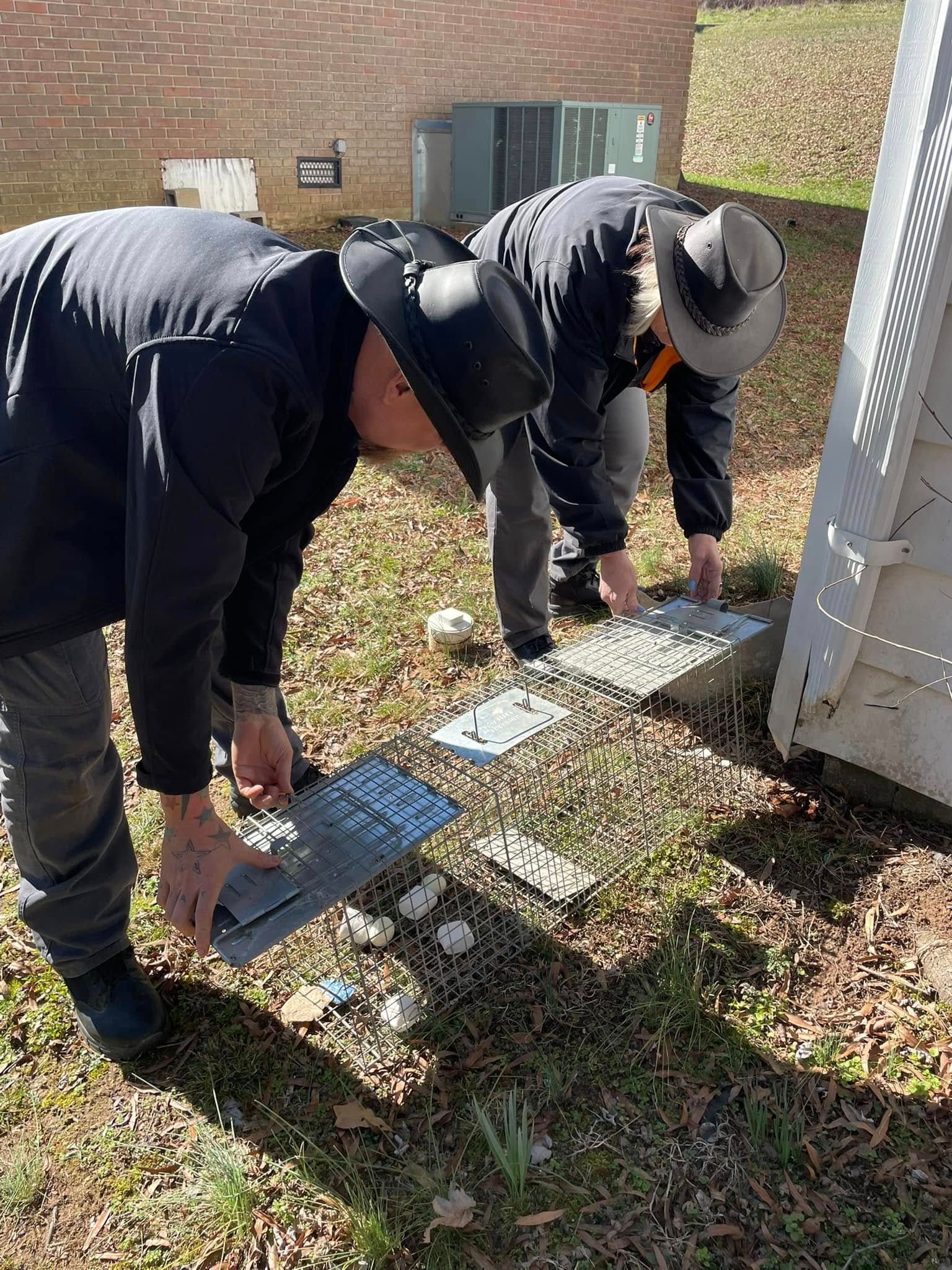 Two men are kneeling down in the grass looking at a piece of paper.