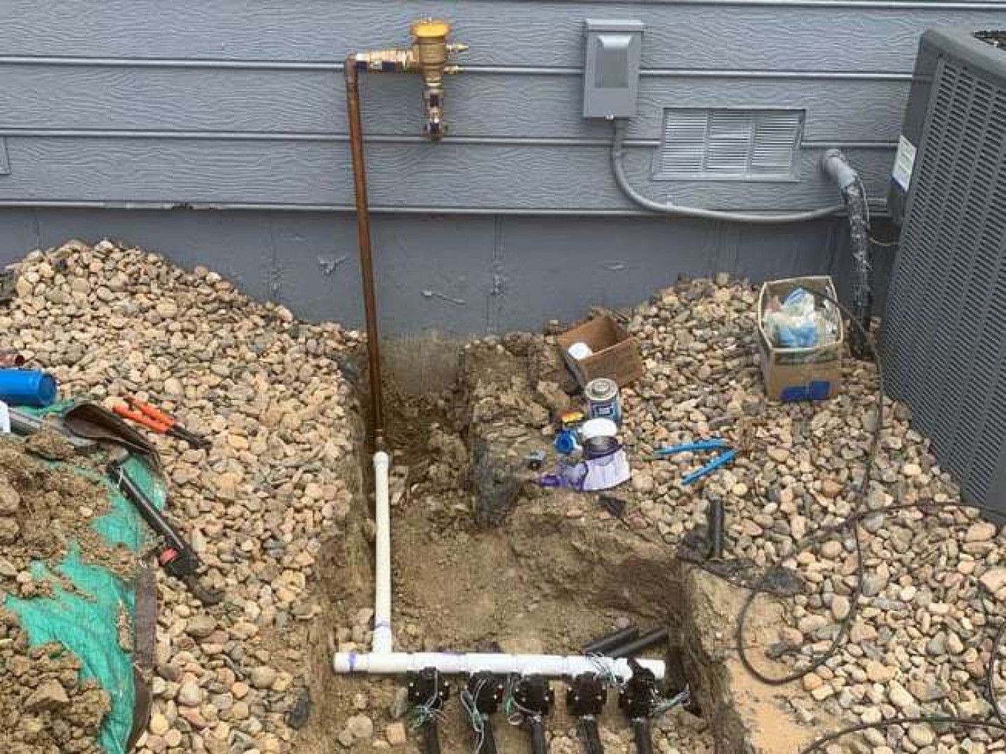 A pipe is being installed in the dirt next to a house.