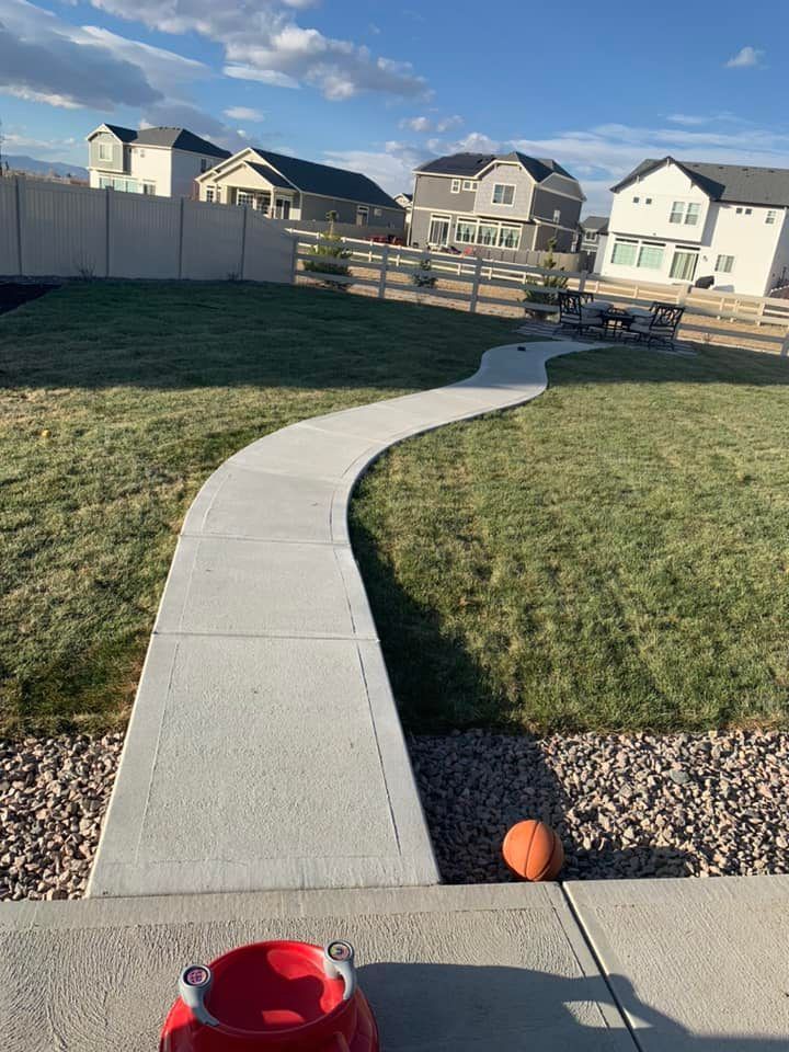 A concrete walkway leading to a pumpkin in a yard.