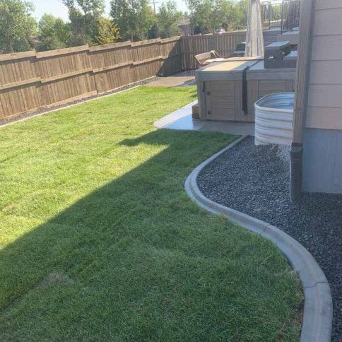 A backyard with a hot tub and a wooden fence.