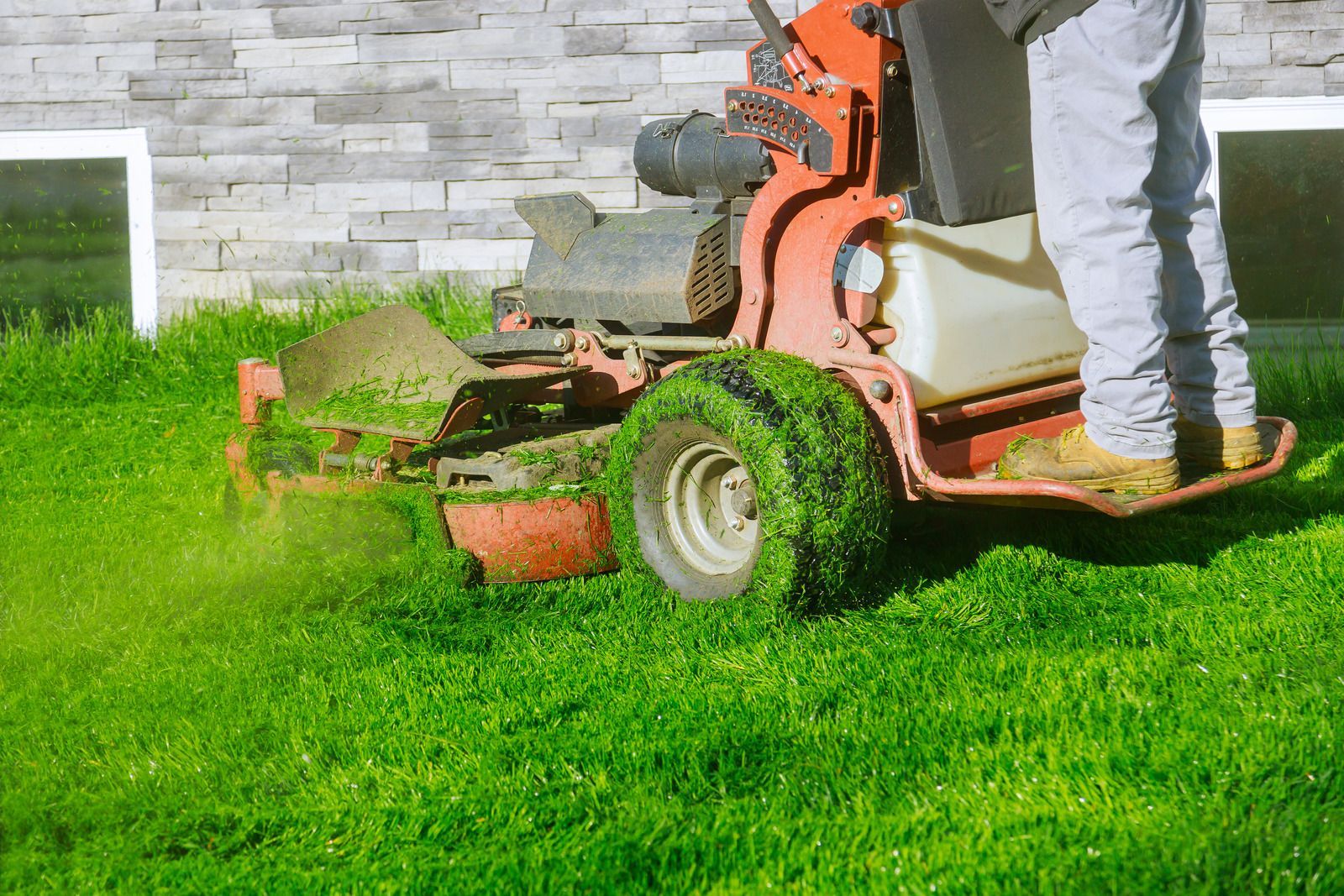 A man is mowing a lush green lawn with a lawn mower.
