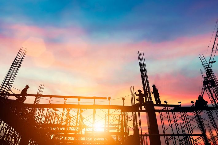 Un gruppo di operai edili sta lavorando a un edificio al tramonto.
