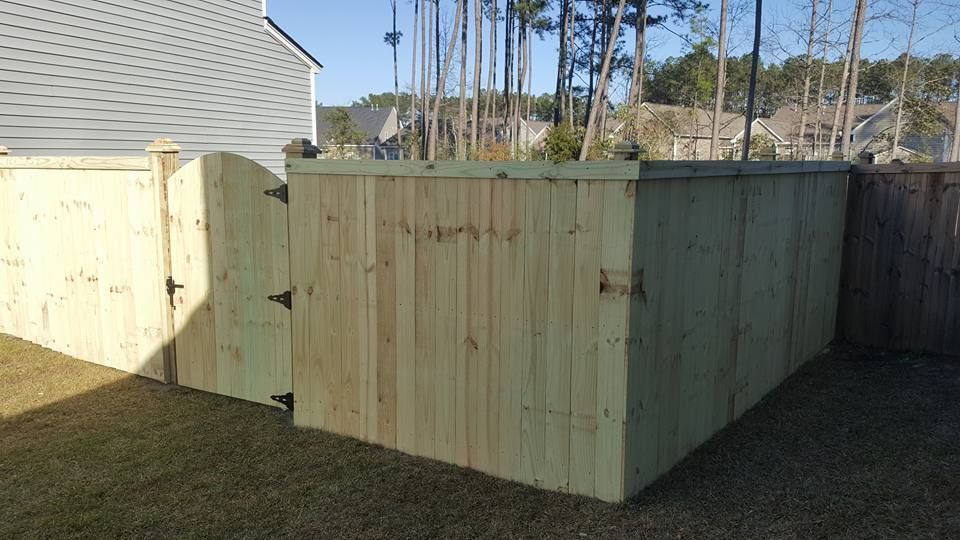 A wooden fence with a gate in the backyard of a house.