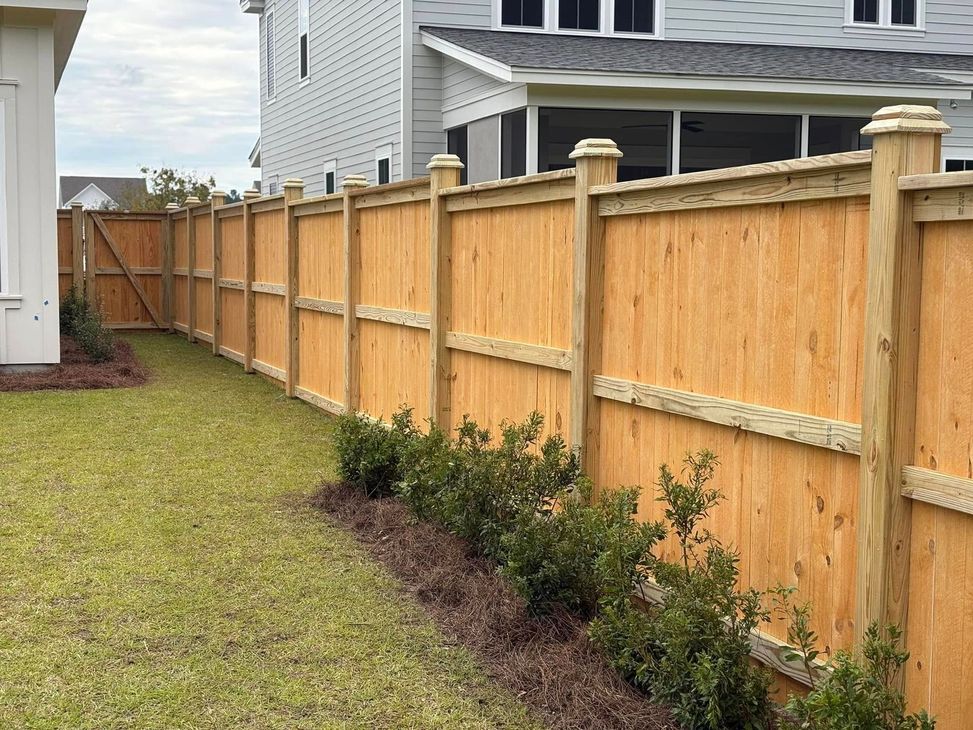 A wooden fence is in the backyard of a house.